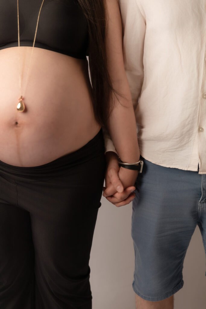 gros plan sur un couple se donnant la main focus sur ventre de femme enceinte grossesse