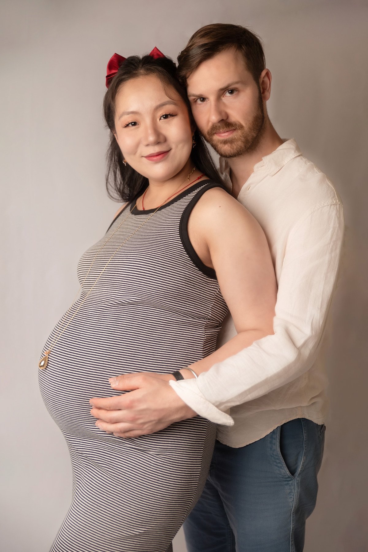 couple dont femme enceinte en studio main de papa sur le ventre grossesse