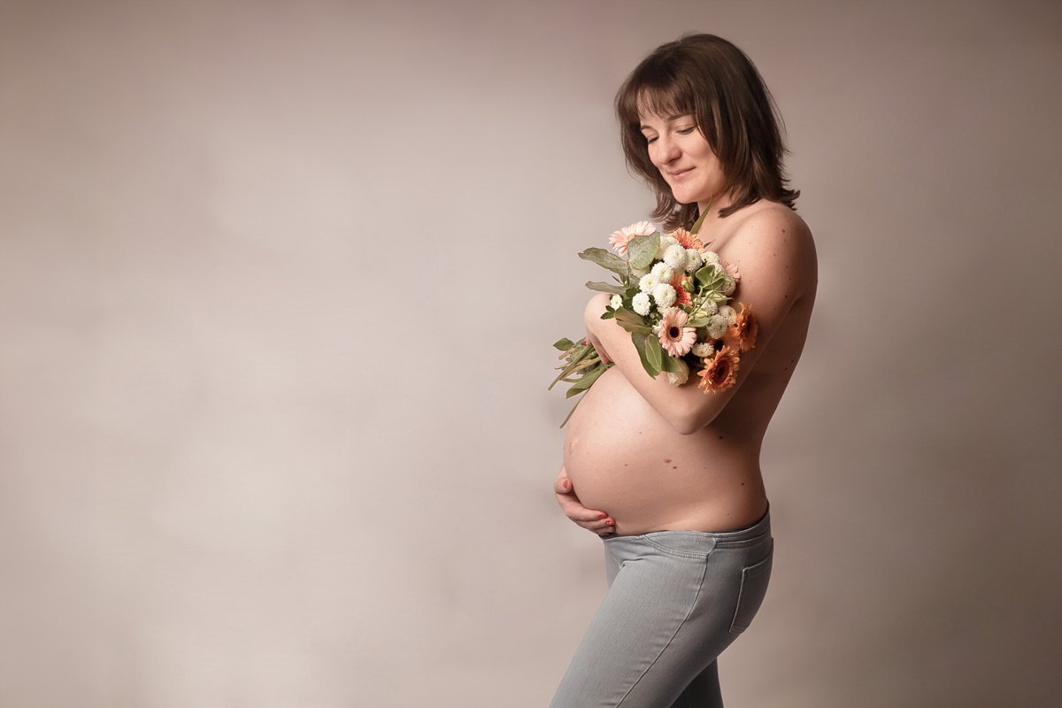 Femme enceinte grossesse en studio avec bouquet de fleurs